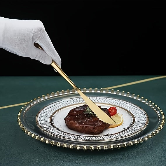 Hand with white glove using a gold knife to cut into a piece of meat on a decorative plate.