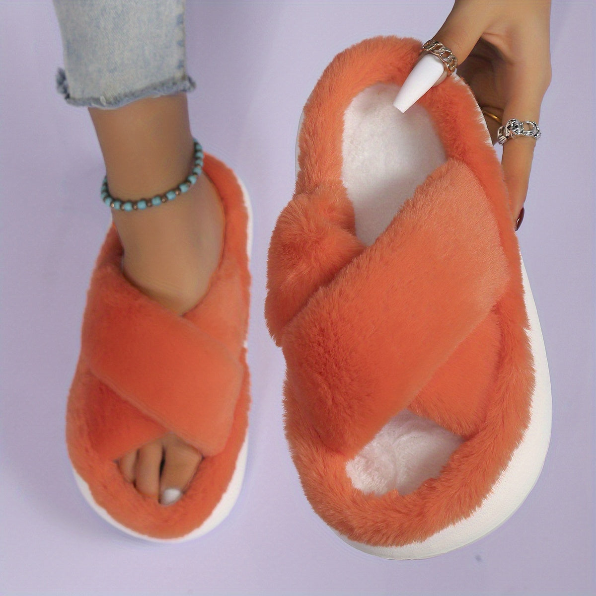 Orange fuzzy slippers worn by a person on a light purple background