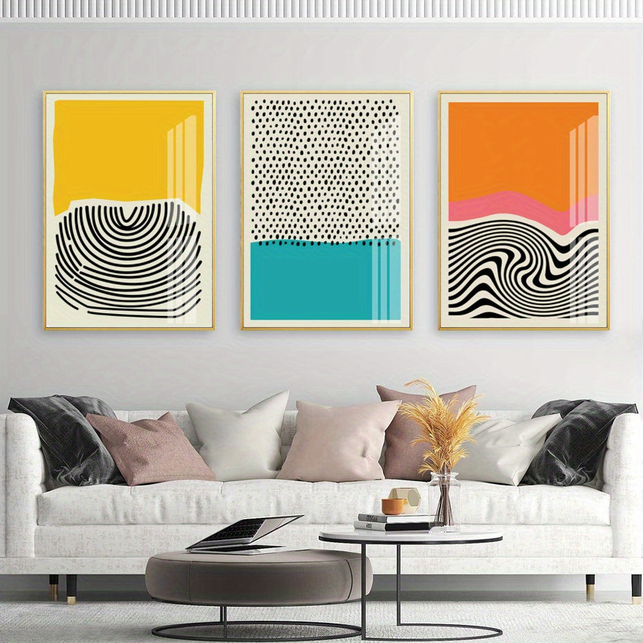 Three abstract art prints on a wall above a white sofa with decorative pillows.