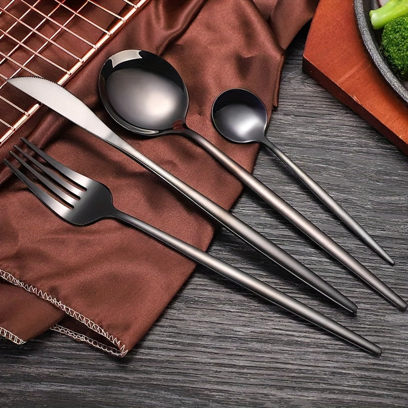 Set of black cutlery including a fork, knife, and two spoons on a brown fabric and wooden surface.