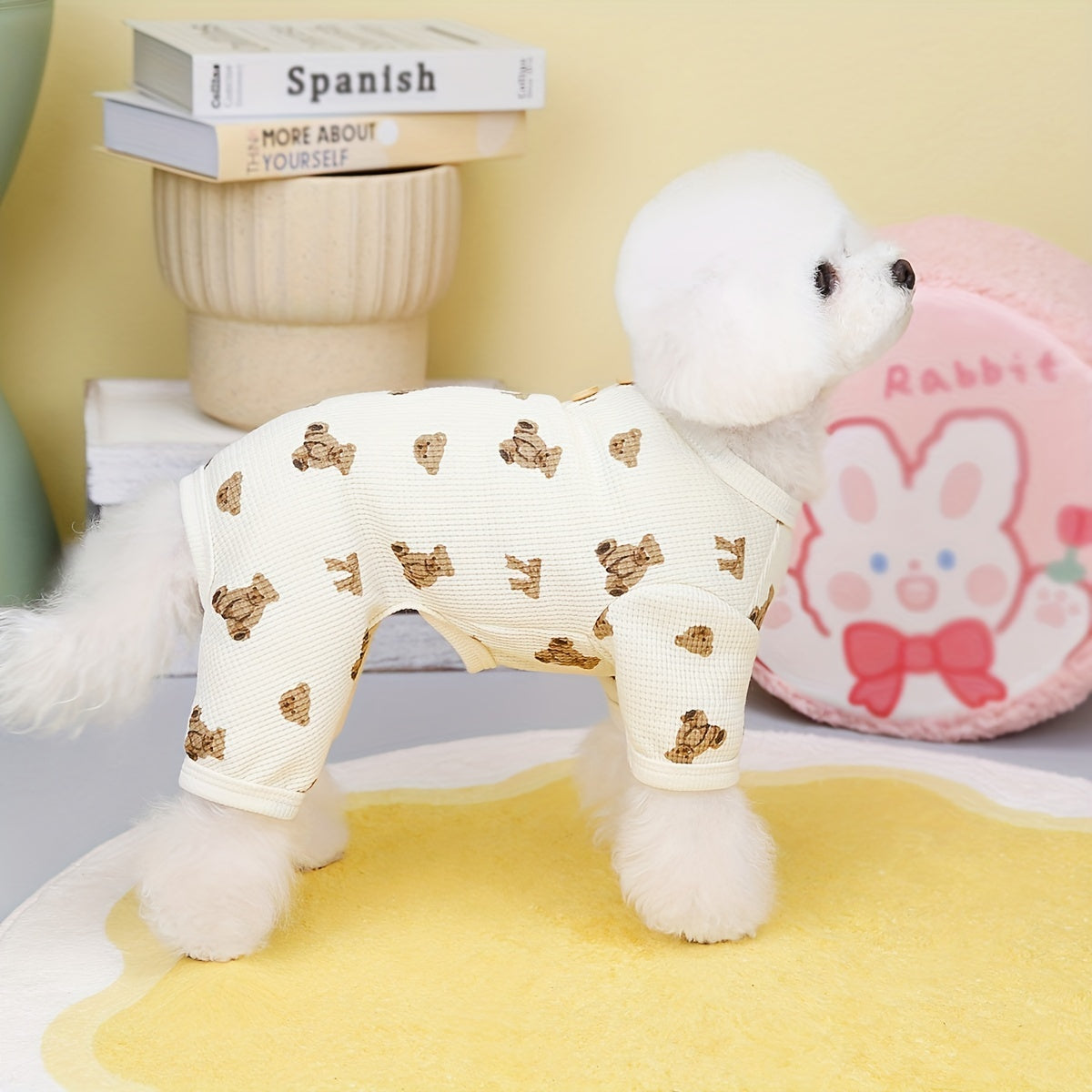 White plush dog toy with gold bow pattern on a yellow surface