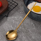 Gold spoon on a gray surface with a bowl of eggs in the background