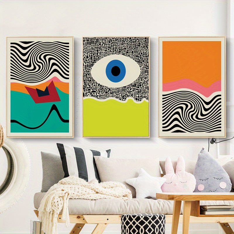 Three abstract art pieces on a wall above a sofa with decorative pillows.