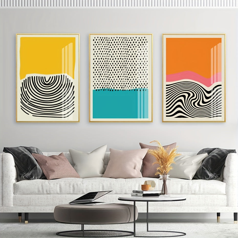 Three abstract art prints on a wall above a white sofa with decorative pillows.