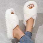White fluffy slippers worn with denim jeans on a gray floor.