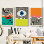 Three abstract art pieces on a wall above a sofa with decorative pillows.