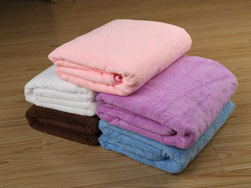 Stack of folded towels in various colors on a wooden floor