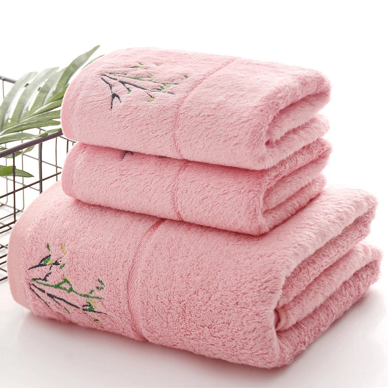Stack of pink towels with floral embroidery on a white background