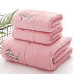 Stack of pink towels with floral embroidery on a white background