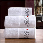 Three white towels stacked on a wooden surface with decorative text and heart designs.