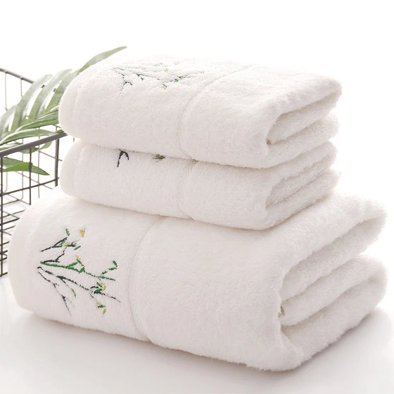Stack of white towels with embroidery on a light background