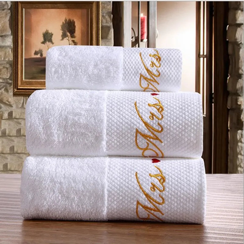 Stack of white towels with 'Mrs.' embroidery on a wooden surface.