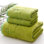 Stack of green towels with bamboo embroidery on a white background