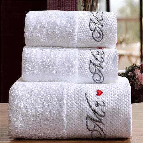 Stack of white towels with 'Mr' and 'Mrs' embroidery on a wooden surface.