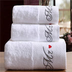 Stack of white towels with 'Mr' and 'Mrs' embroidery on a wooden surface.