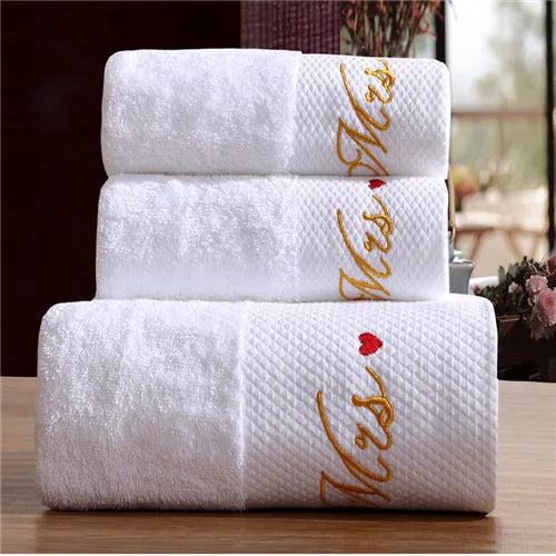 Stack of white towels with gold and red text on a wooden surface