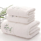 Stack of white towels with embroidery on a light background
