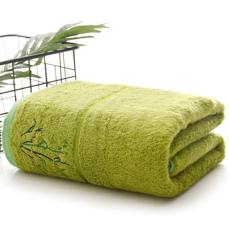Folded green towel with bamboo design on a white surface