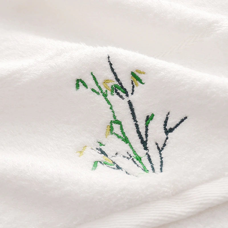Embroidered design of branches and leaves on a white fabric background