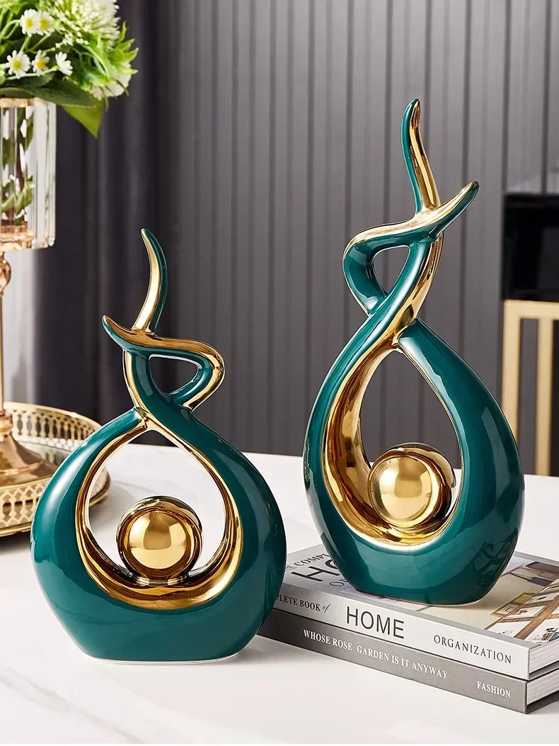 Two decorative vases with gold and teal finish on a surface with a blurred background.