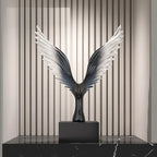 Decorative sculpture of wings on a black base against a striped wall.