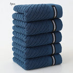 Stack of five blue towels with visible brand labels on a white background