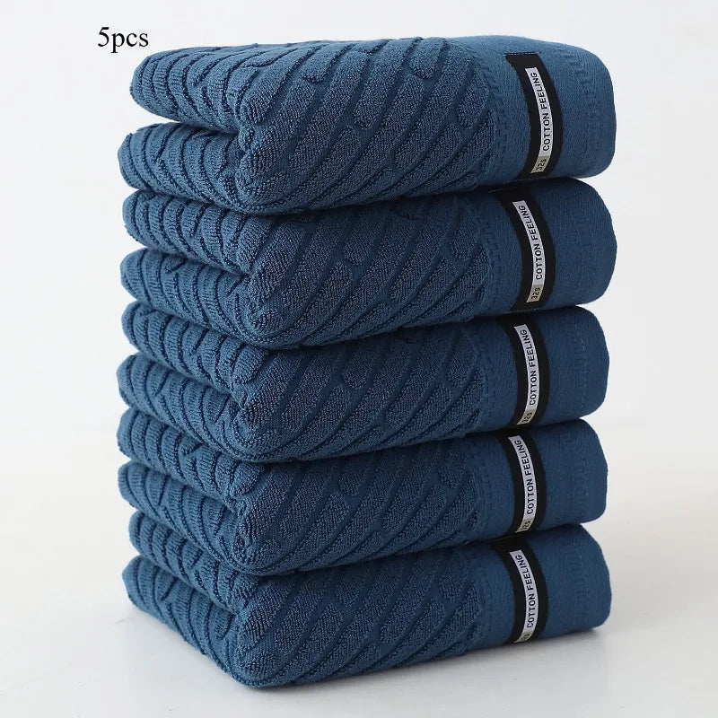 Stack of five blue towels with visible brand labels on a white background