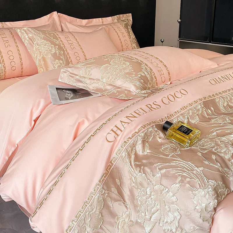 Pink bedding set with floral patterns and 'CHANEL'S COCO' branding, featuring a bottle of perfume.