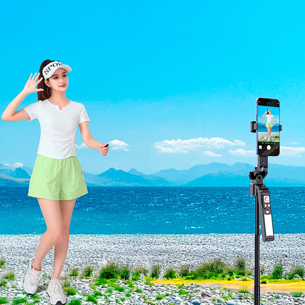 Woman in golf attire standing on a beach with a phone on a tripod recording her.