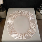 Pink satin headband on a white surface with a blurred background