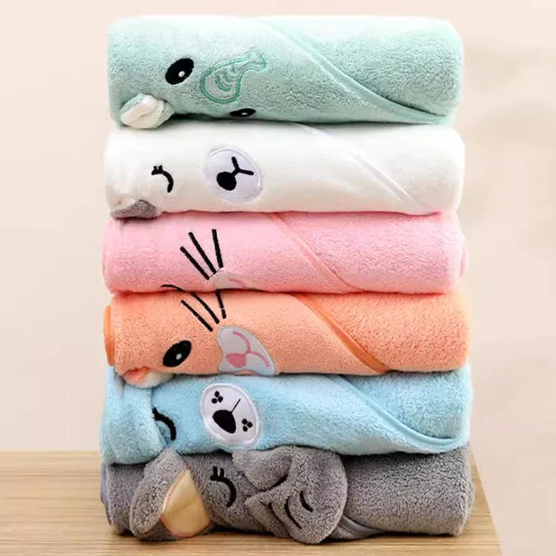 Stack of colorful towels with cartoon animal faces on a wooden surface