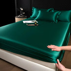 Green satin sheet set on a bed with a hand adjusting it.