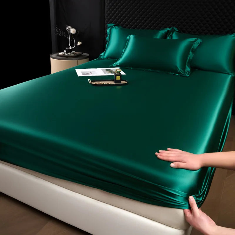 Green satin sheet set on a bed with a hand adjusting it.