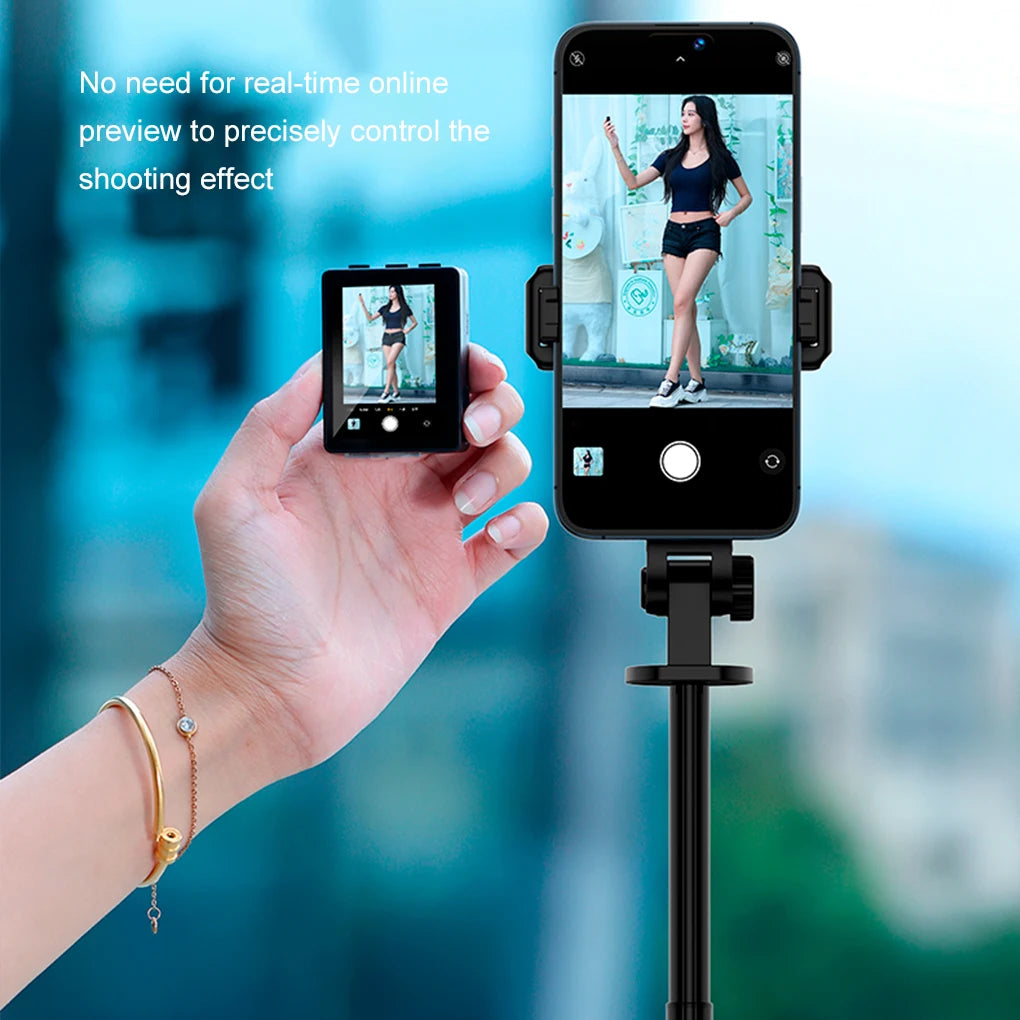 Hand holding a smartphone with a camera app open, displaying a live feed of a person in a mirror. Another smartphone is on a stand, showing a similar live feed.