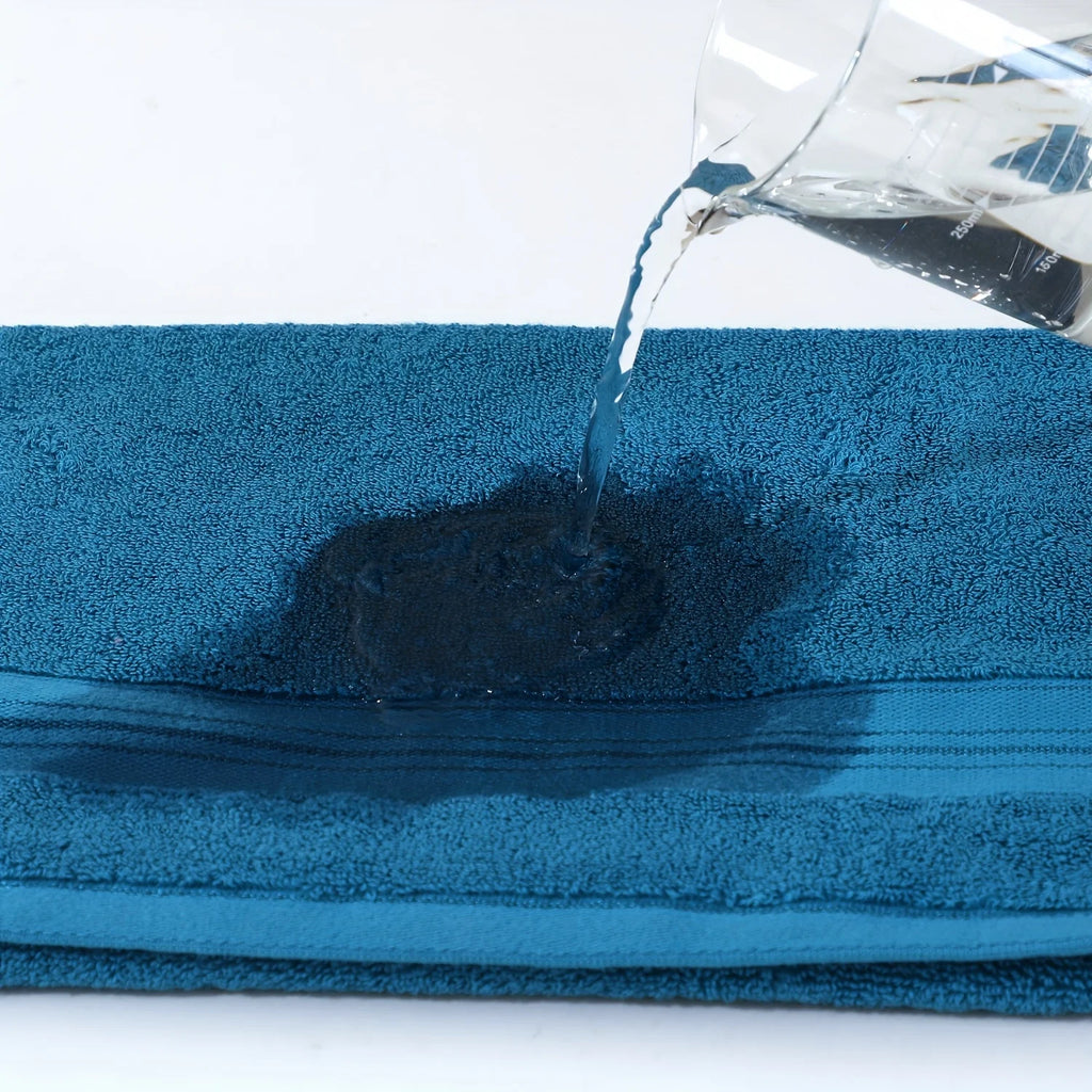 Blue towel with water being poured onto it, showing absorbency.