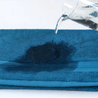Blue towel with water being poured onto it, showing absorbency.