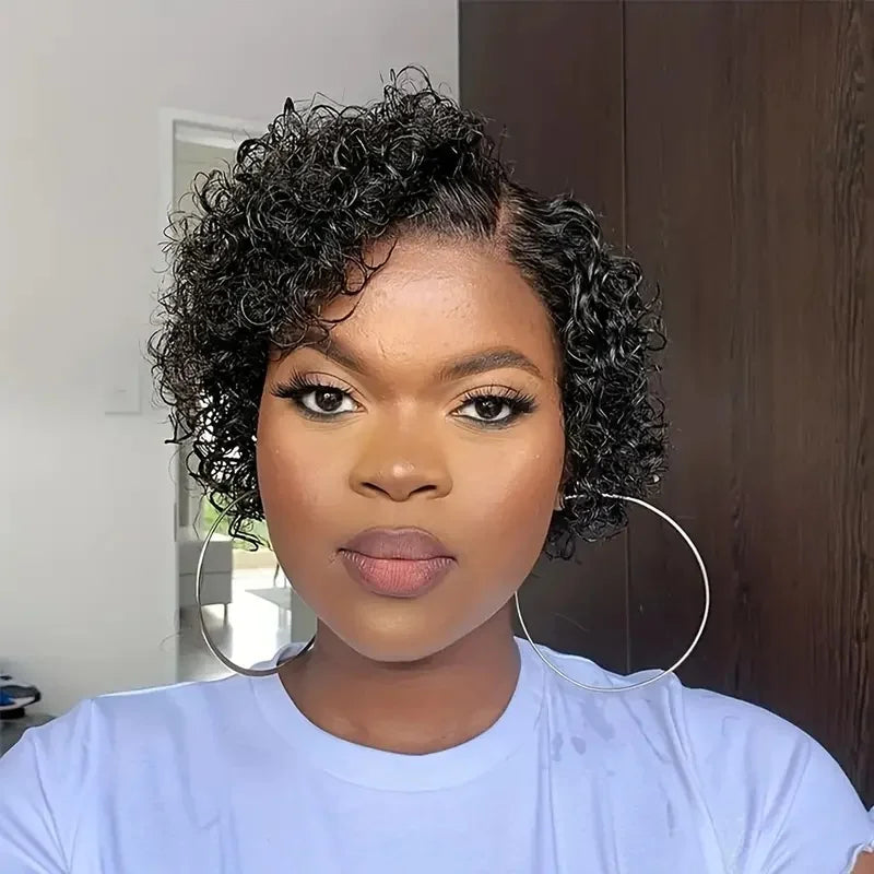 Woman with short, curly hair wearing a light blue shirt indoors.
