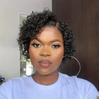 Woman with short, curly hair wearing a light blue shirt indoors.
