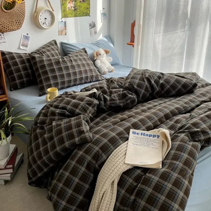 Bed with plaid bedding and a 'Be Happy' towel in a cozy bedroom setting.