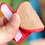 Small red and beige shoe model held by a hand with a blurred background