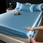 Blue satin sheet set on a bed with a person's hand touching it.