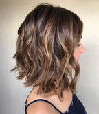 Side profile of a person with shoulder-length hair with brown and blonde balayage on a plain background