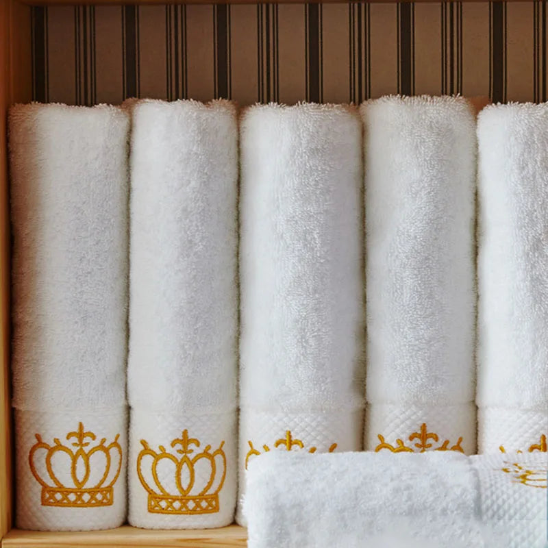 Set of white towels with gold crowns arranged in a row.