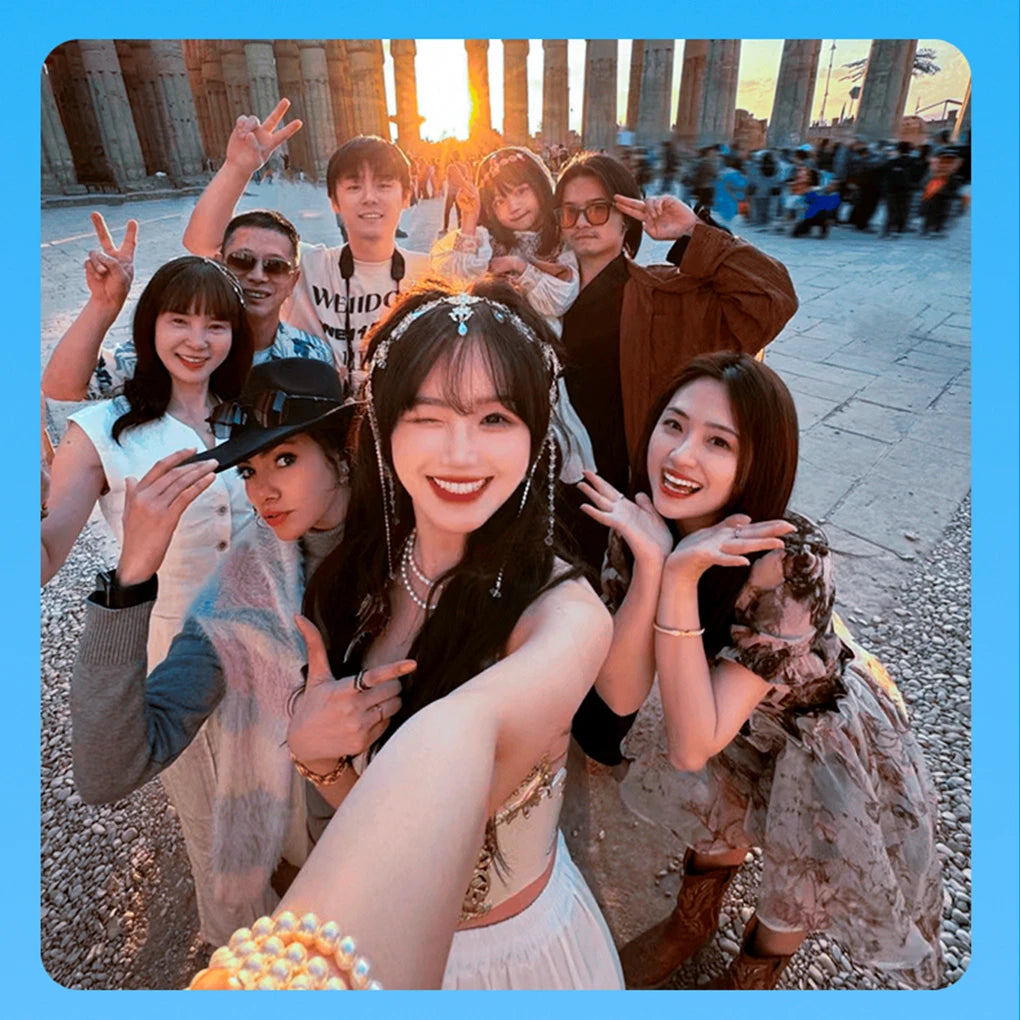 Group of people posing for a photo in front of ancient ruins with a blue border.