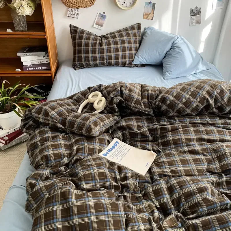 Plaid comforter on a bed with pillows and books in the background