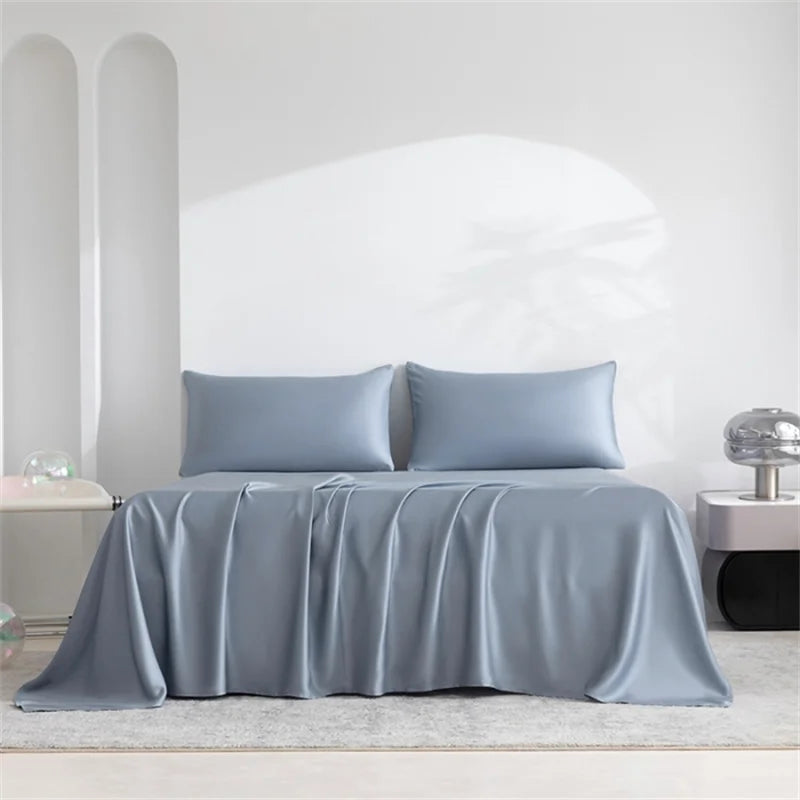 Gray bedspread and pillows on a bed in a minimalistic room.
