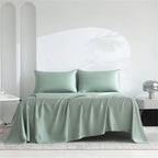 Green satin sheet set on a bed with a white headboard.