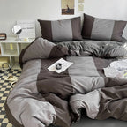 Gray and brown checkered bedding set on a bed in a room with a mirror and shelf.