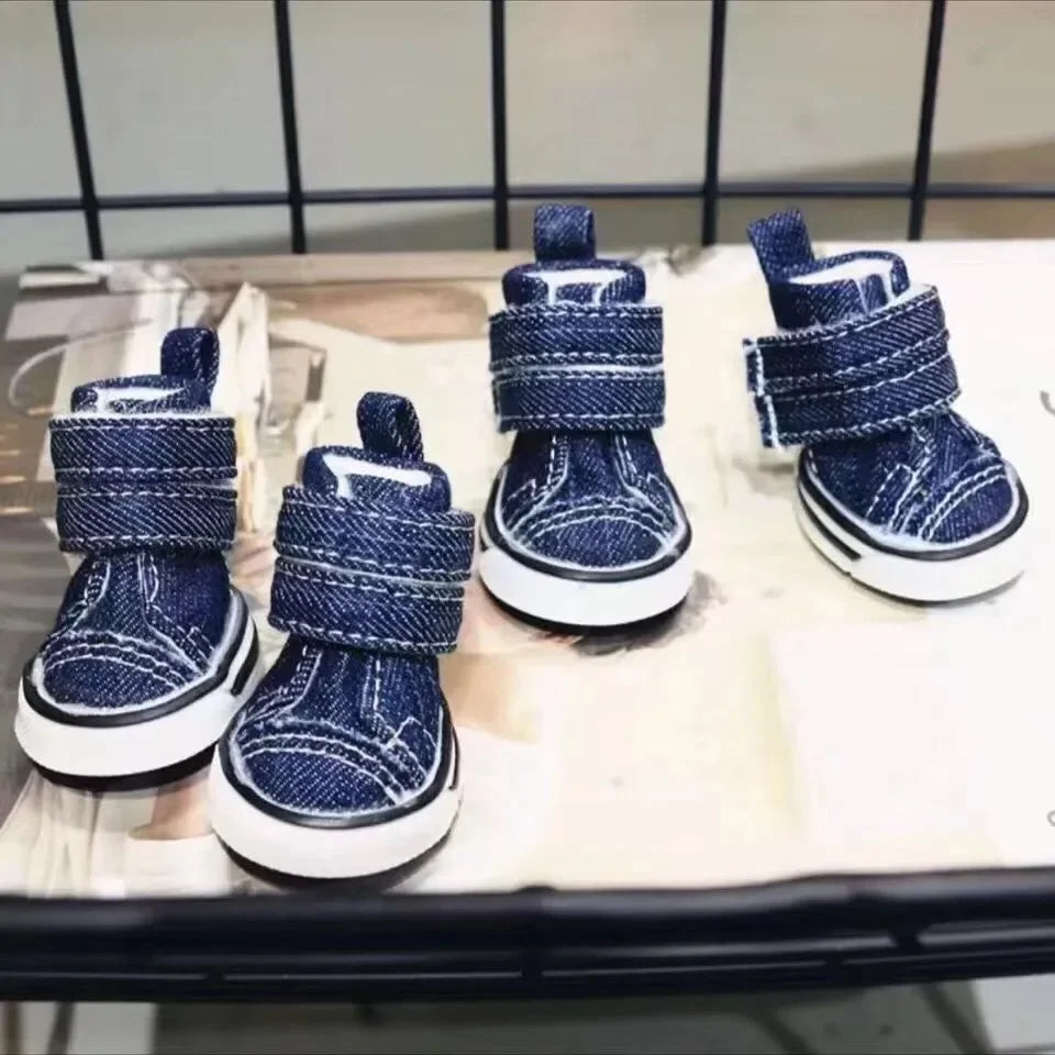 Pair of blue denim dog boots on a metal surface.