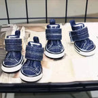 Pair of blue denim dog boots on a metal surface.